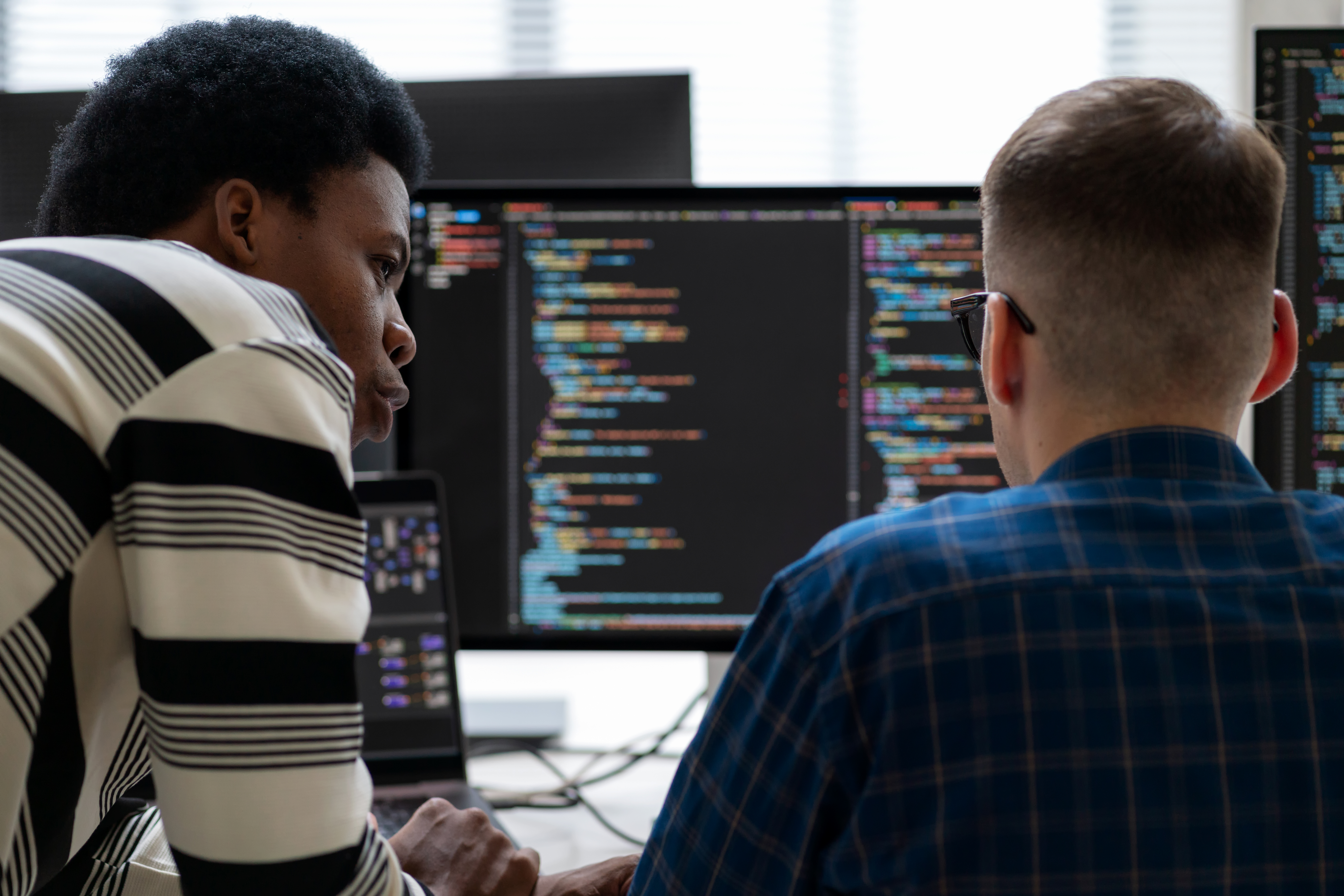 Two people coding on a computer.