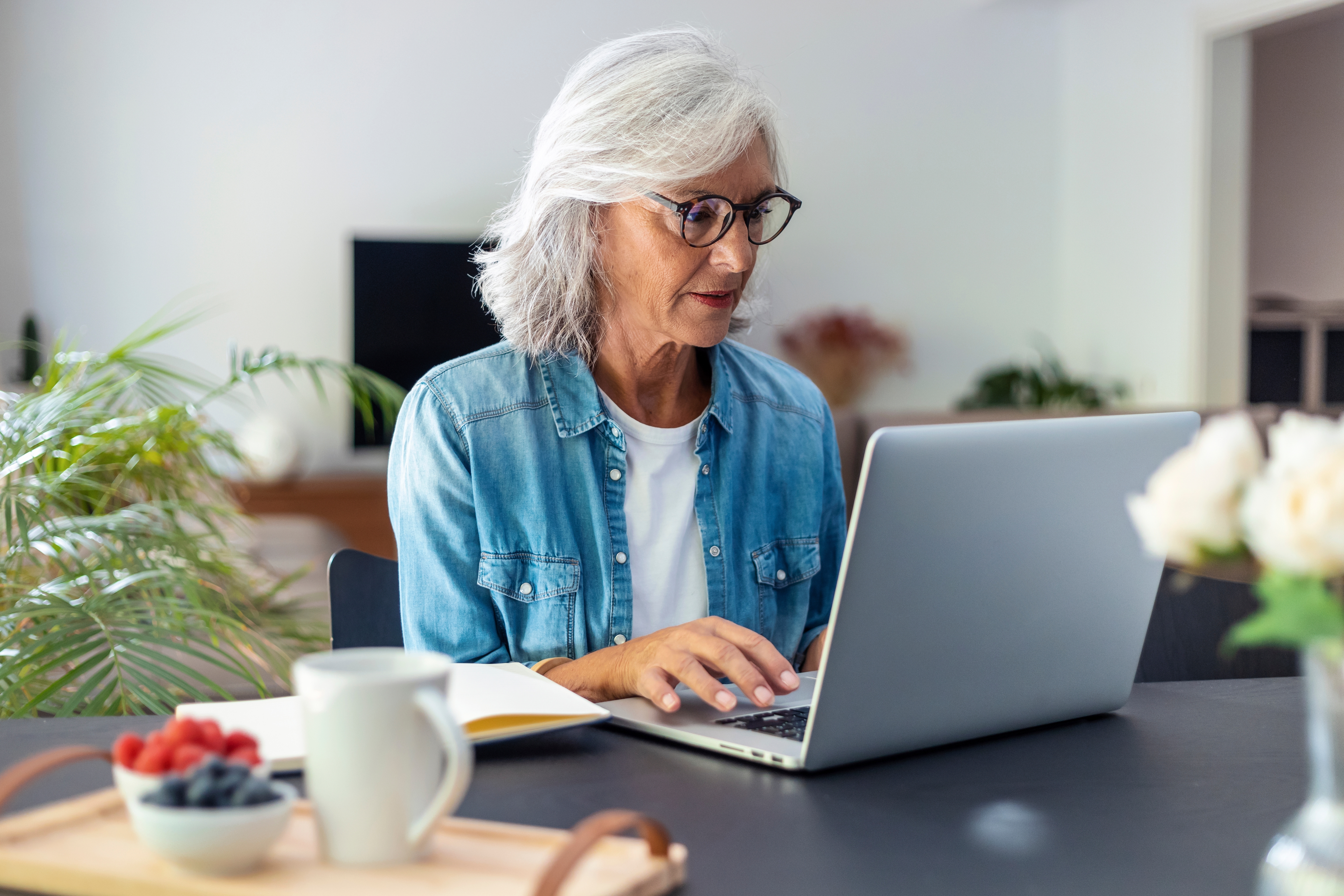 A woman sitting at the dining room table looking at her laptop
