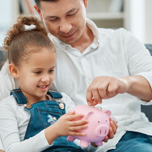 dad and daughter putting money into piggy bank