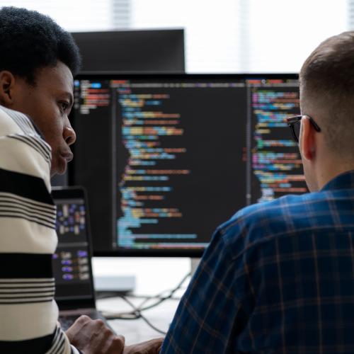 Two people coding on a computer.