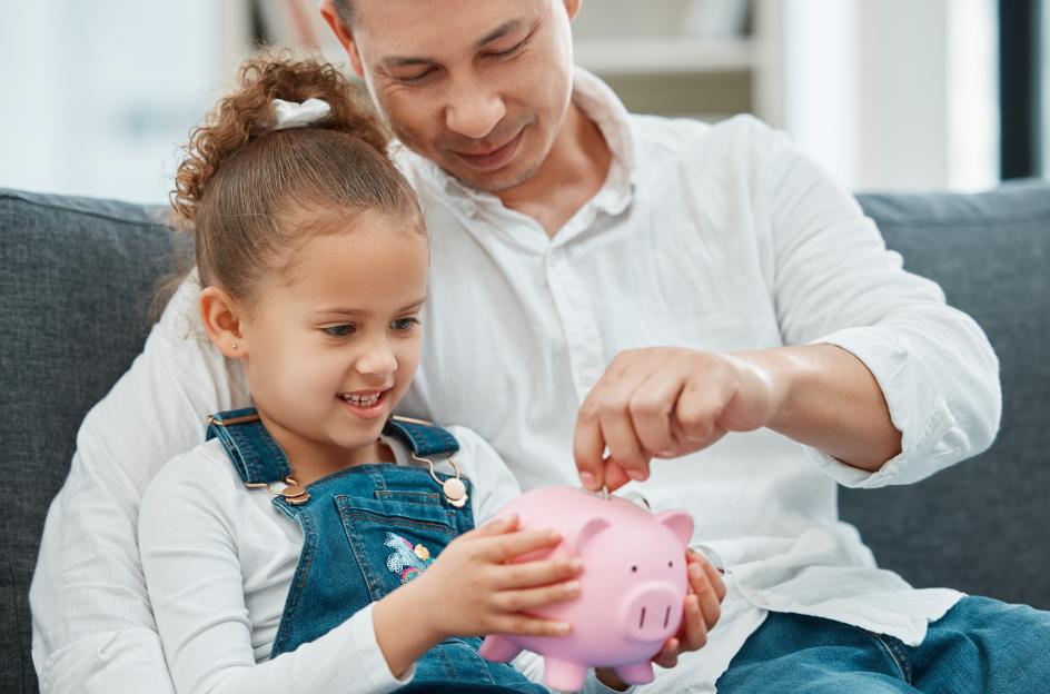 dad and daughter putting money into piggy bank