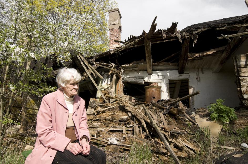 woman in front of her damaged home after a disaster.