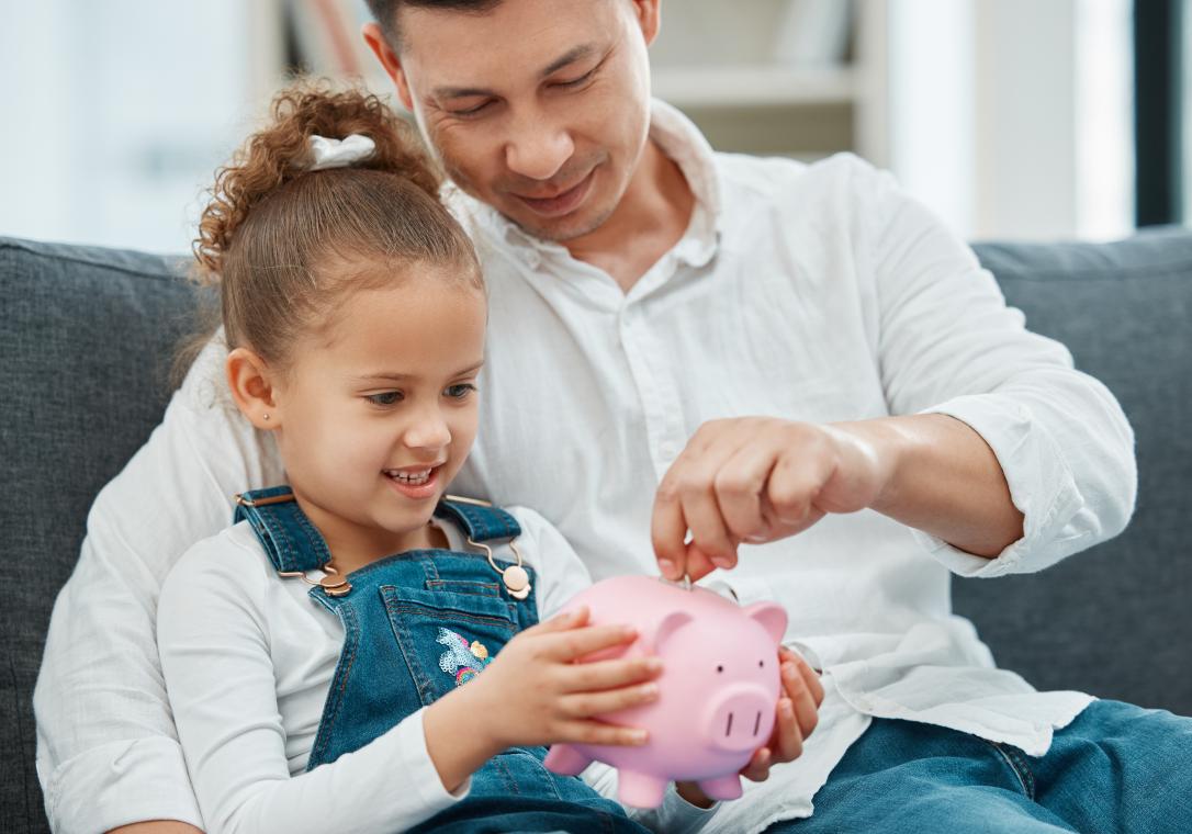 dad and daughter putting money into piggy bank